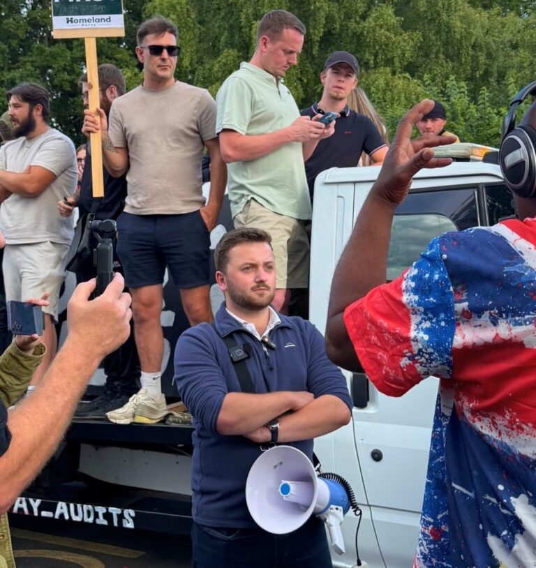 Callum Barker (front) stands with a megaphone at the rallying point for a demonstration outside the Bell Hotel in Epping